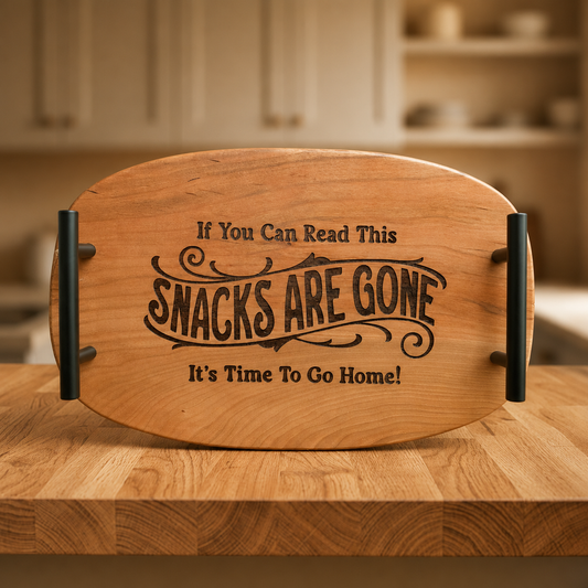 A wooden snack tray with black metal side handles, engraved with the humorous phrase 'If You Can Read This SNACKS ARE GONE It's Time To Go Home!', displayed on a wooden countertop with a blurred kitchen background.