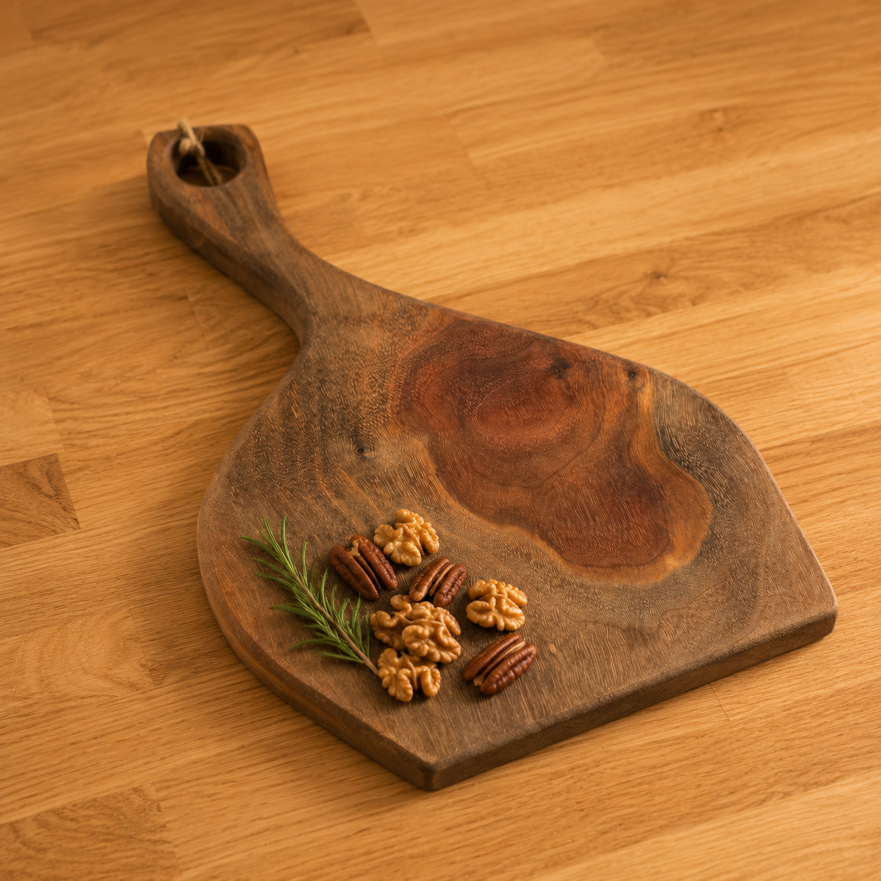 A rustic walnut serving board with a handle, shown on a light wood tabletop. The board has a natural dark brown grain pattern and is styled with walnuts, pecans, and a sprig of rosemary.