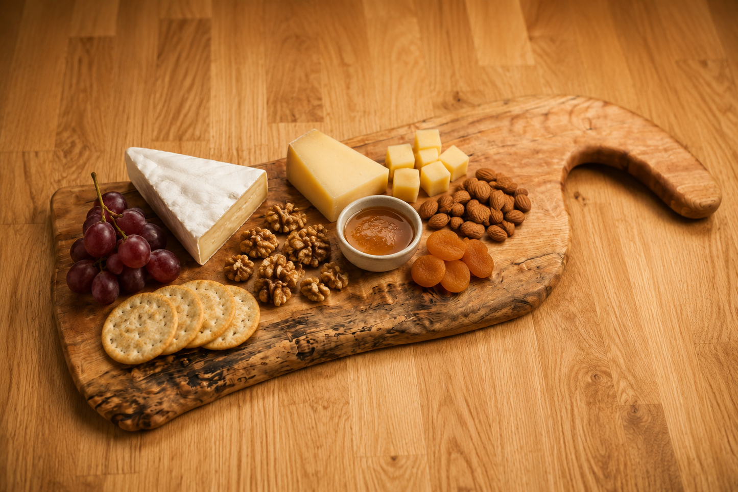 A rustic live edge maple charcuterie board styled with cheese wedges, crackers, grapes, walnuts, dried apricots, and a small bowl of dip on a warm wood tabletop.